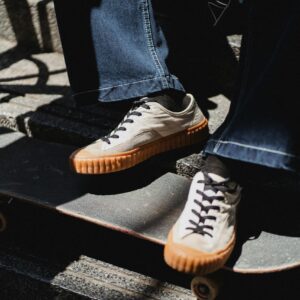 Close-up of sneakers resting on a skateboard on outdoor stairs.